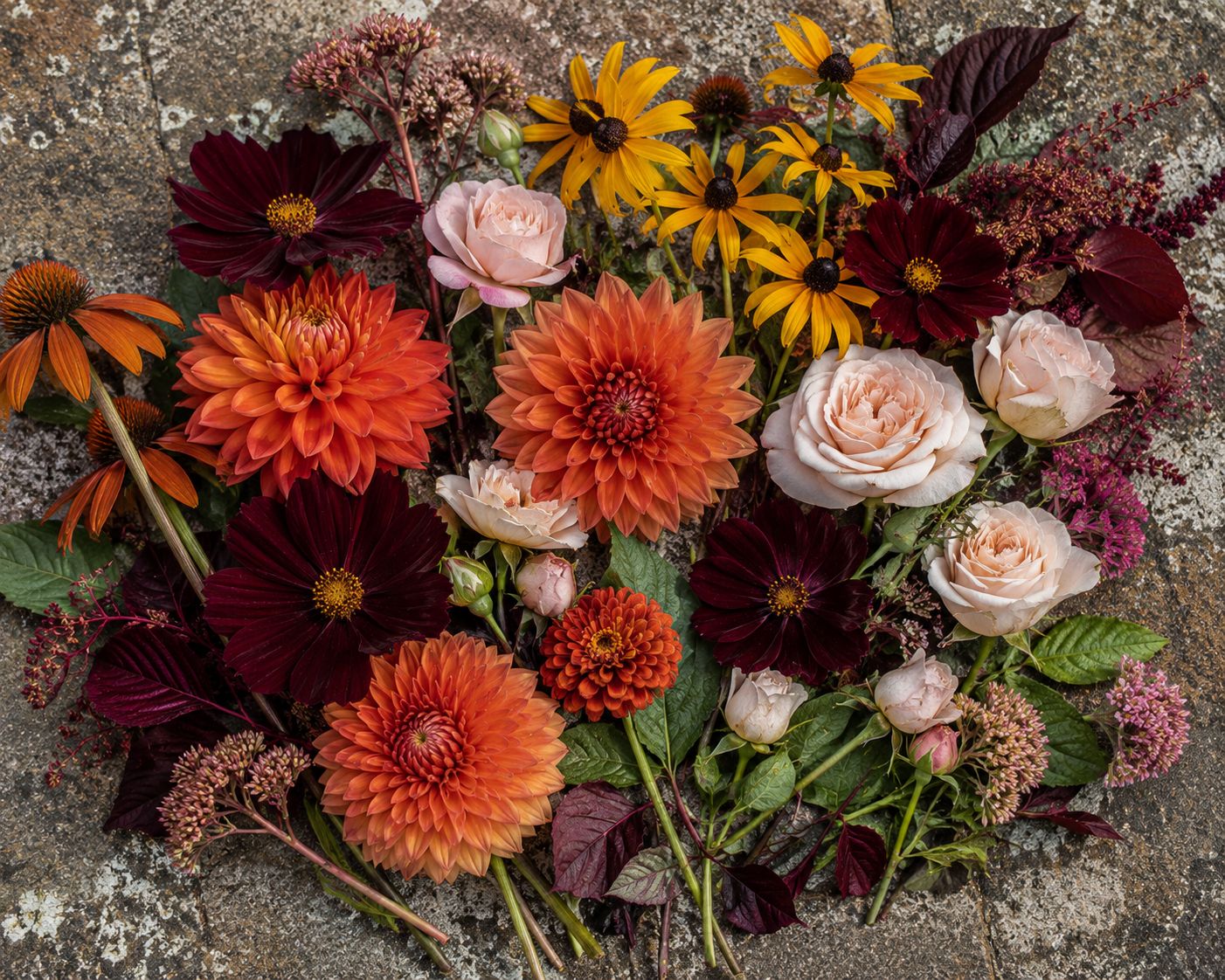 Overhead styled flat-lay of dahlias, cosmos, rudbeckia and roses in a warm jewel-toned colour palette